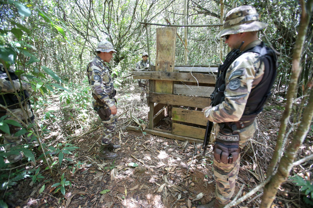 Policiais do Grupamento de Operações no Cerrado (GOC) fiscalizam armadilha encontrada na mata. 