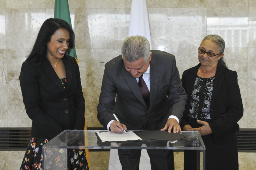A defensora pública-geral do DF, Maria José Silva Souza de Nápolis, acompanhada da mãe, Maria Soledade da Silva Souza; e o governador Rodrigo Rollemberg no momento da assinatura do termo de posse.
