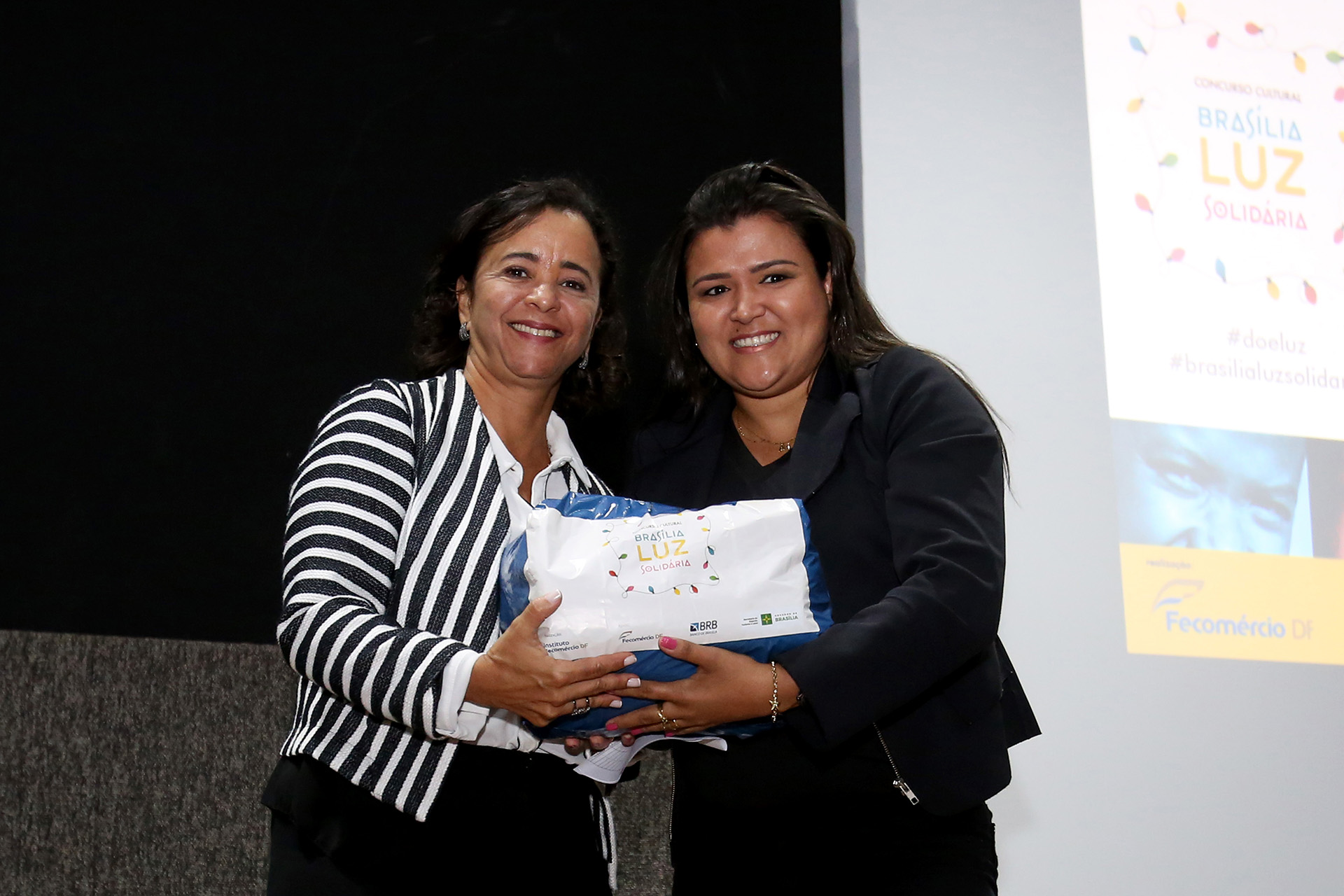 A colaboradora do governo Márcia Rollemberg entrega cesta básica para Ana Lúcia da instituição Lar de São José