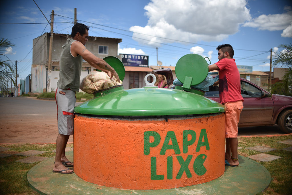 Dois homens descartam lixo em um papa-lixo no Pôr do Sol, em Ceilândia